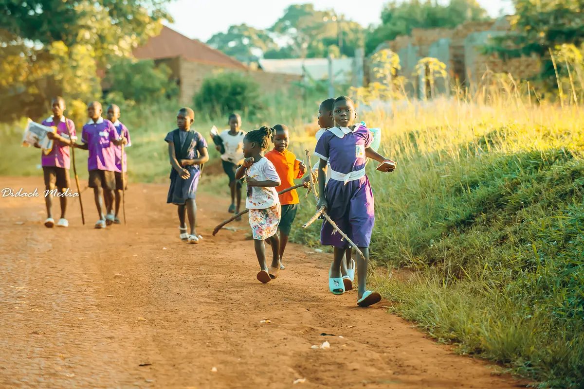Children run to school carrying sticks used to light the fire for preparing lunch at school.