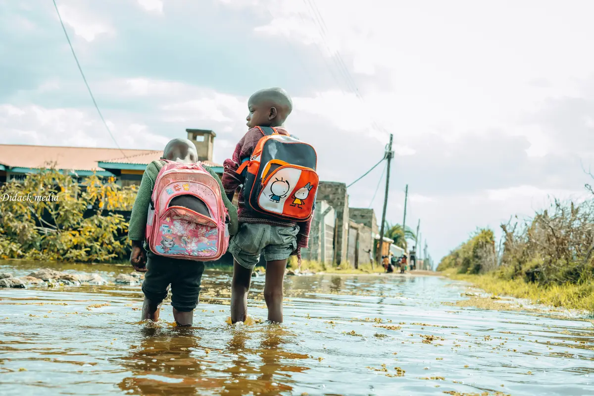 A boy holds his younger brother’s hand as they walk through floodwaters in Naivasha.