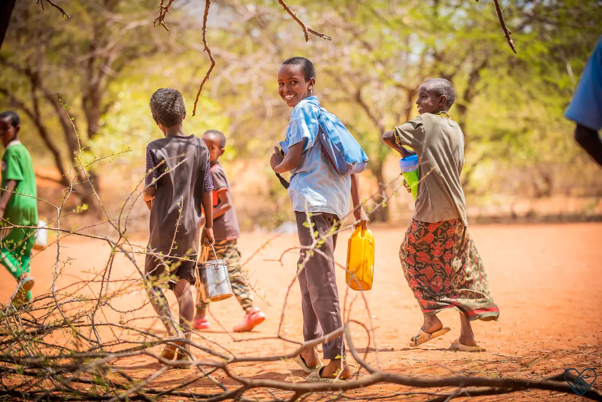 Smiling children walk home from school in Wajir, carrying food to support their families.