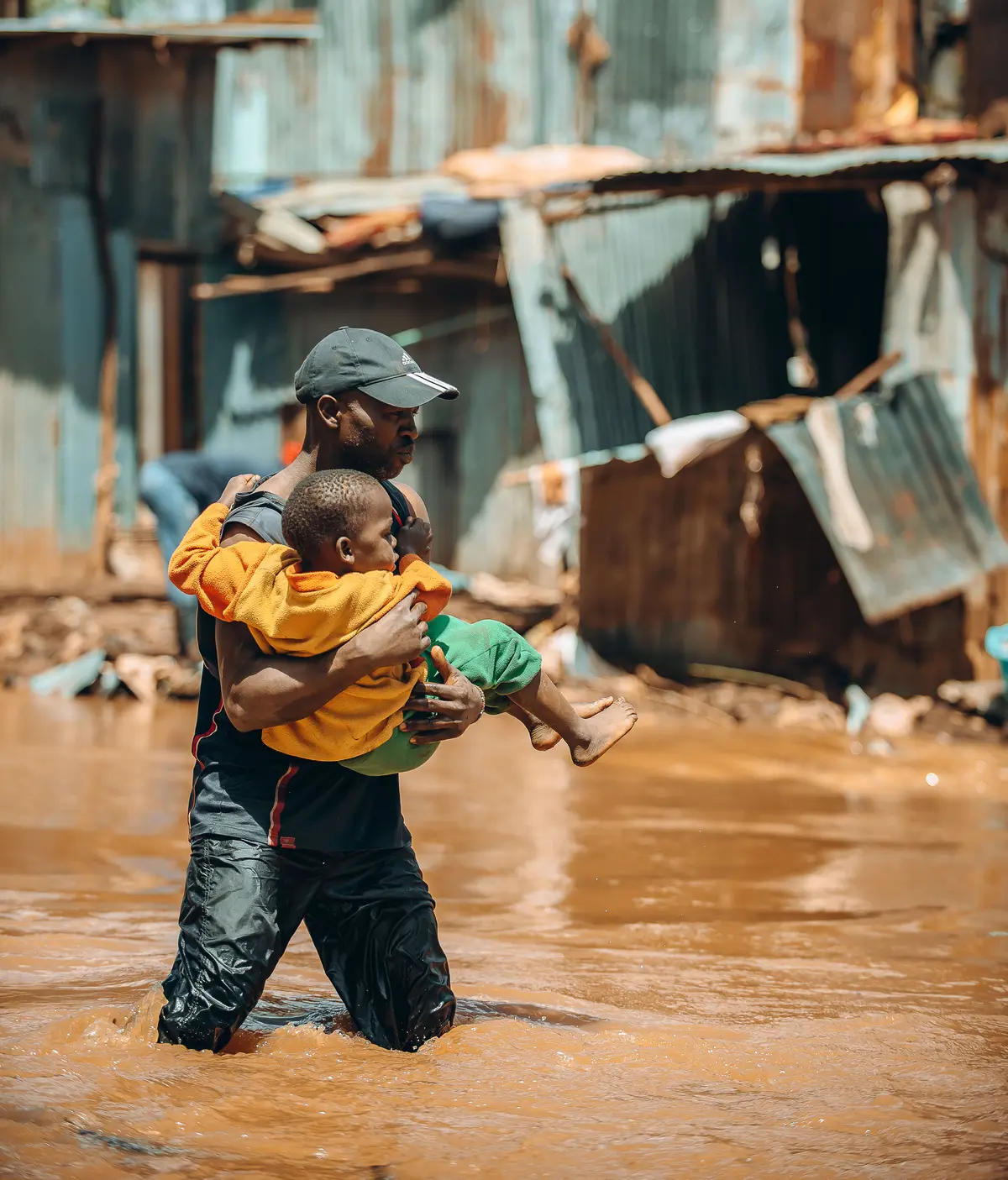 A man rescuing a child from a flooded house in Mathare slum