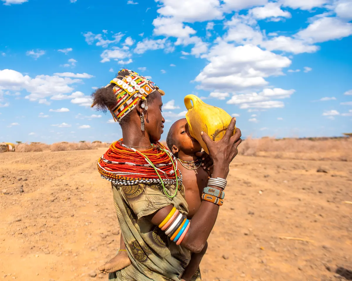 A mother gives water to her child in Marsabit under the harsh heat of the sun.