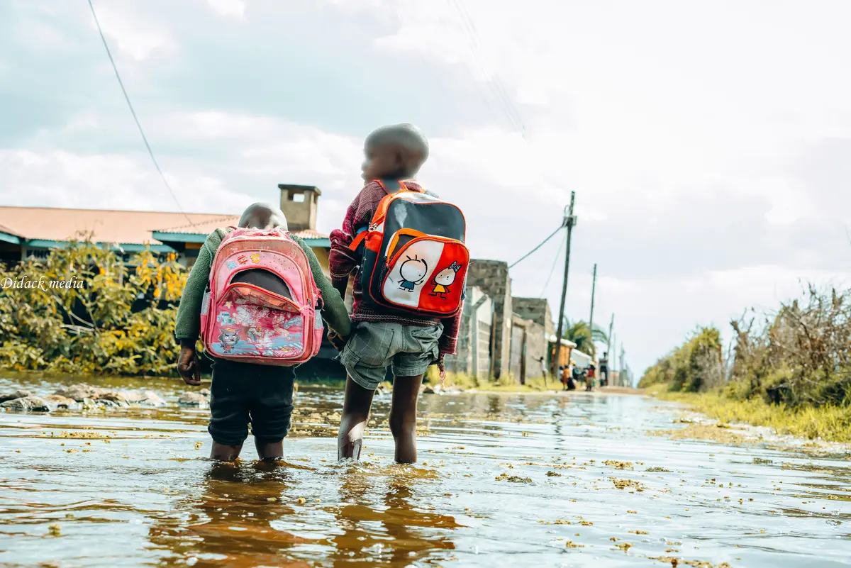 Children walking through stagnant floodwaters after school in Kihoto, Naivasha.